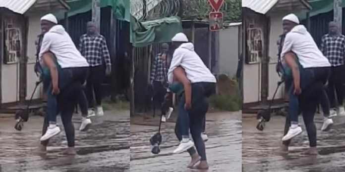 “The guy fit be last born” – Reactions as lady backs her man to cross flooded road (Video)