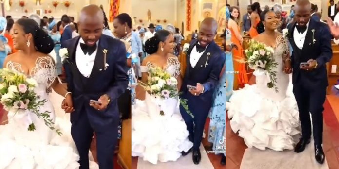 Netizens react to trending video of groom engrossed in his phone while walking down the aisle with his bride (WATCH)